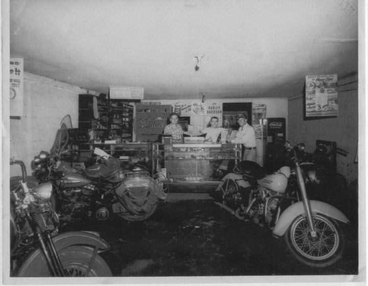 Inside the original Dothan Powersports store, three men behind the counter with motorcycles on the floor